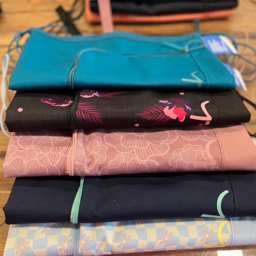 Stack of colorful yoga pants with floral and abstract designs on a wooden surface.