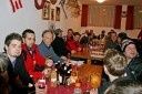 Eine Gruppe von Menschen sitzt an einem Tisch in einem Restaurant, einige tragen Jacken, mit Flaschen und Gläsern auf dem Tisch.