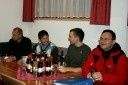Vier Männer sitzen an einem Tisch mit mehreren Bierflaschen vor ihnen. Sie scheinen in ein Gespräch vertieft zu sein.