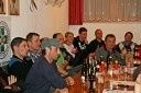Eine Gruppe von Menschen sitzt um einen Tisch in einem Raum, wahrscheinlich für eine Besprechung. Flaschen und Gläser stehen auf dem Tisch. Einige von ihnen tragen Mützen.