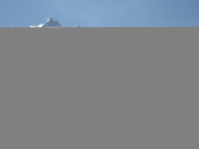 Ein klarer blauer Himmel mit einem entfernten Berggipfel am Horizont, teilweise von Wolken bedeckt.