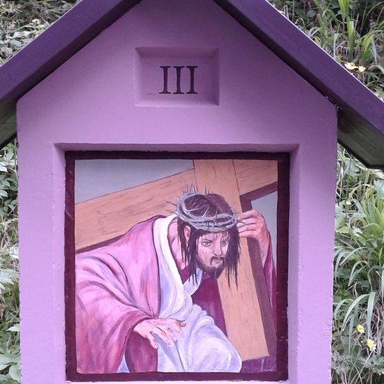 Ein lilafarbenes Haus mit einem Bild von Jesus, der das Kreuz trägt, beschriftet mit 'III'.