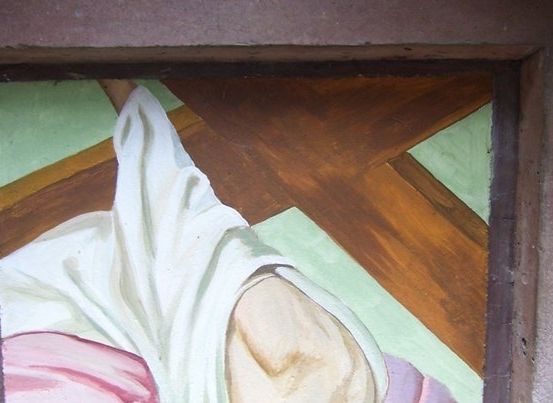 Ein gerahmtes Gemälde zeigt eine Figur, die auf einem Kreuz liegt, wobei ein weißer Stoff die untere Hälfte des Körpers bedeckt. Der Hintergrund ist grün und braun.