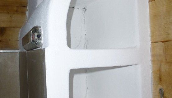 Ein Nahaufnahme einer weißen Schaumstoffisolierung mit einem angehängten Metallobjekt, das an einer Holzwand platziert ist.