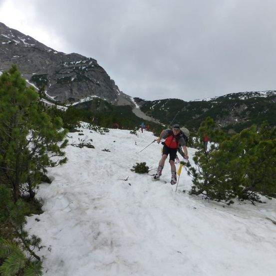 Ein Mann skilang auf einem schneebedeckten Berghang, mit Skistöcken.