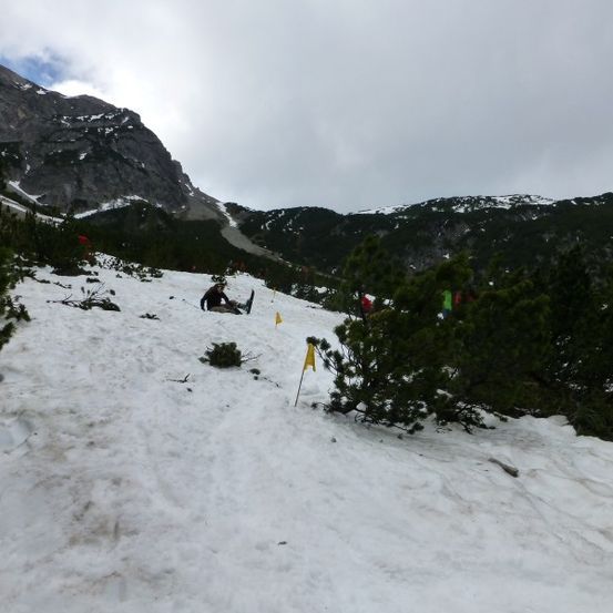 Eine Person rutscht den schneebedeckten Berghang hinunter, gekennzeichnet durch gelbe Flaggen.