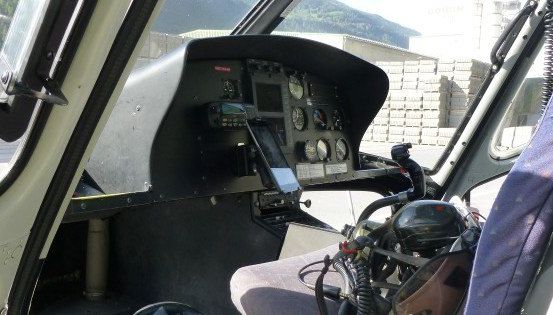 Das Cockpit eines Hubschraubers mit verschiedenen Steuerungen und einem Smartphone auf dem Armaturenbrett.