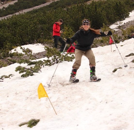 Ein Skifahrer bewegt sich auf einem verschneiten Hang, ein gelber Flaggenpfad weist den Weg. Ein weiterer Skifahrer folgt dahinter.