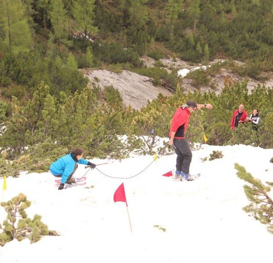 Eine Gruppe von Menschen skifahrer auf einem verschneiten Berg mit Flaggen, die den Weg markieren.