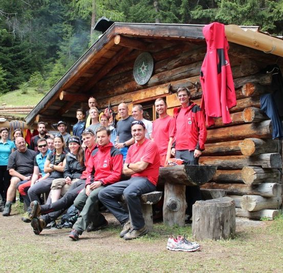 Eine Gruppe von Menschen in roten Jacken posiert für ein Foto vor einer Holzhütte.