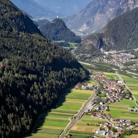Eine Luftaufnahme eines Tals mit einem Fluss, einer Stadt und von Bäumen bedeckten Bergen.
