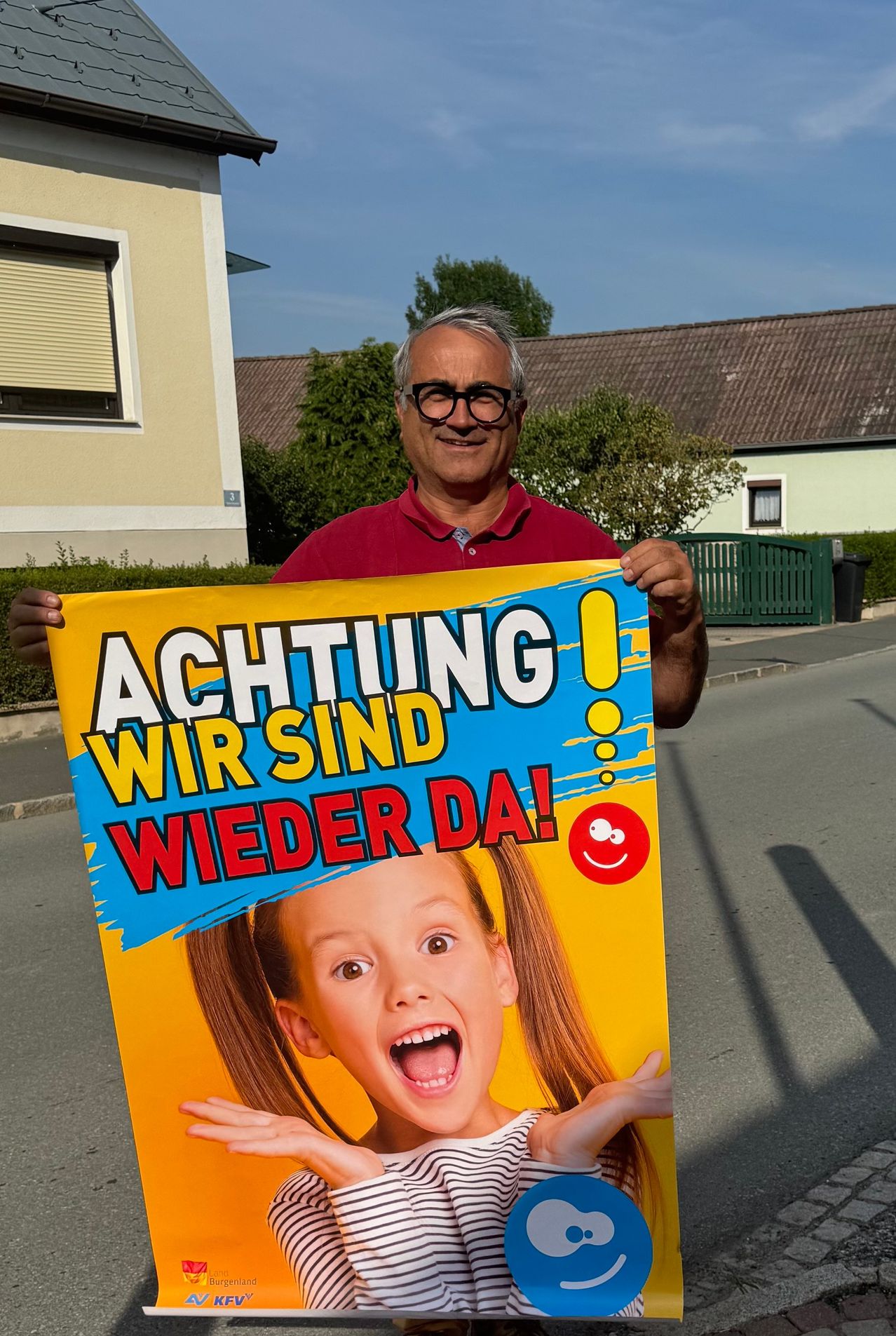 Ein Mann, der ein Schild hält, auf dem Achtung! Wir sind wieder da! steht, mit einem Bild eines überraschten Mädchens.