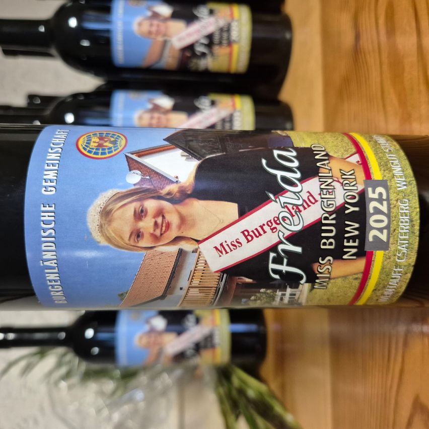 Weinflasche mit dem Etikett 'Freya' und 'Miss Burgenland'. Die Flasche steht auf einer Holzoberfläche, mit anderen Flaschen im Hintergrund.