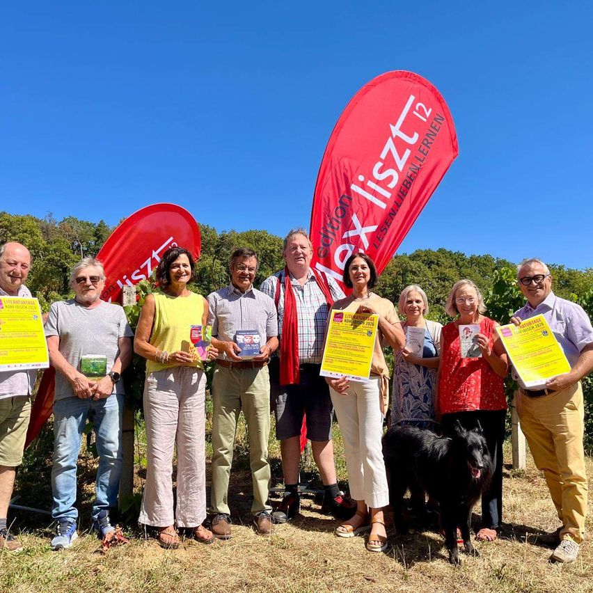Literaturtage mit Menschen und Büchern vor roten Fahnen in einem Weingarten