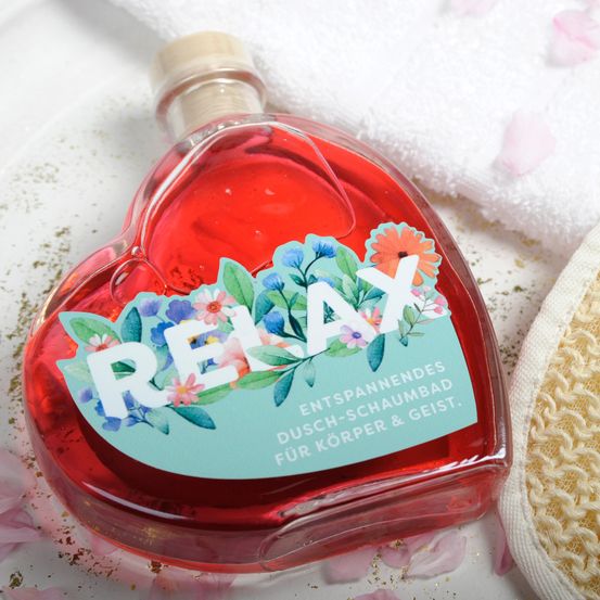 Eine herzförmige Flasche mit roter Flüssigkeit im Inneren. Das Etikett hat Blumendesigns und das Wort 'RELAX'. Die Flasche ist von rosa Blütenblättern umgeben.
