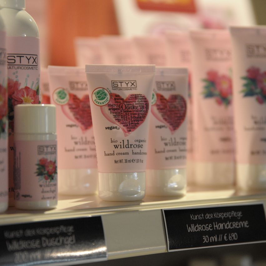 Ein Regal zeigt mehrere Tuben Handcreme. Die vordere Tube hat 'Styx' und 'Bio wildrose'. Dahinter sind weitere Tuben mit 'Styx' und 'Wildrose'.