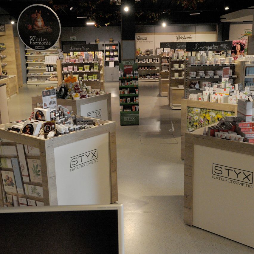 Ein Geschäft mit Holzregalen und ausgestellten Produkten, einschließlich Kosmetik. Das Schild steht für 'Styx Naturcosmetic' und der Hintergrund hat ein Winterharmonie-Thema.