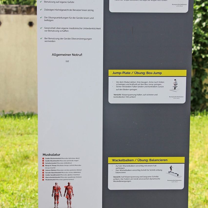 Ein Schild mit Anweisungen zur Verwendung verschiedener Übungsgeräte. Es enthält Details zu einer Sprungplatte, einem Wackelball und listet die von den Geräten beanspruchten Muskeln auf. Die Anweisungen sind in Deutsch.