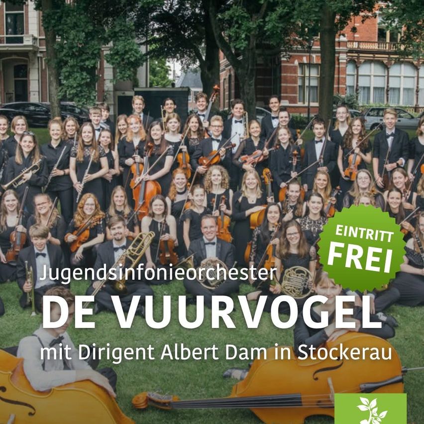 Ein Jugendsinfonieorchester namens DE VUURVOGEEL, unter der Leitung von Dirigent Albert Dam, posiert für ein Foto auf einem Rasen mit Gebäuden und Bäumen im Hintergrund.
