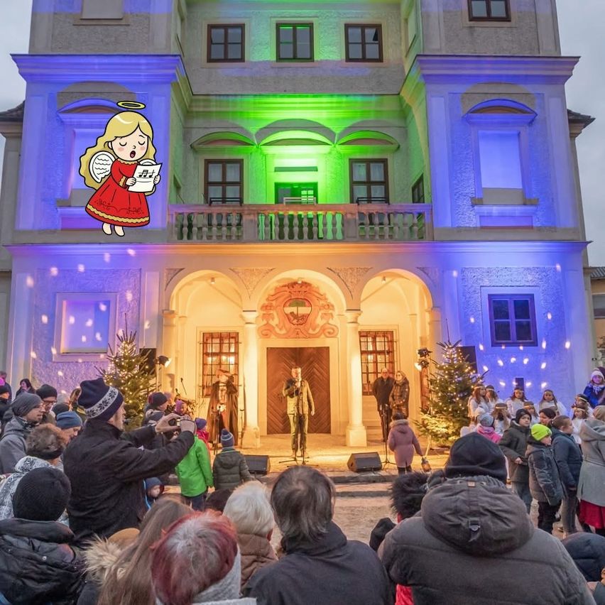 Eine Menschenmenge versammelt sich nachts vor einer Kirche, die mit Weihnachtslichtern und Tannenbäumen geschmückt ist, und Menschen singen und stehen vor einer Bühne.