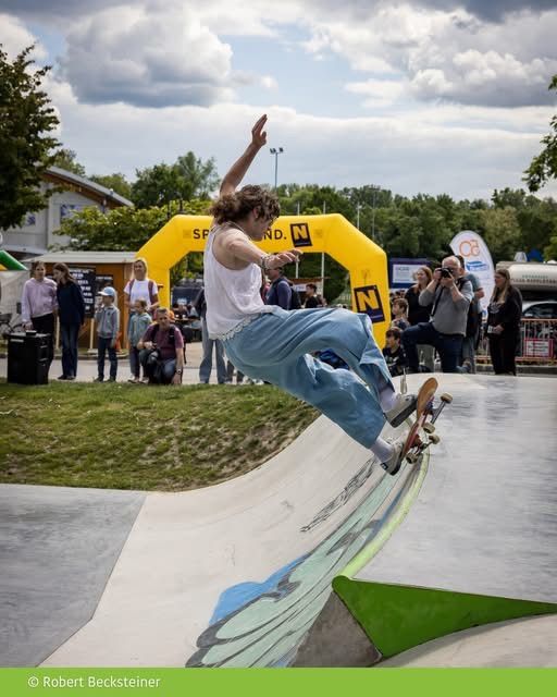 A skater performs a trick on a ramp while several people watch and take pictures.