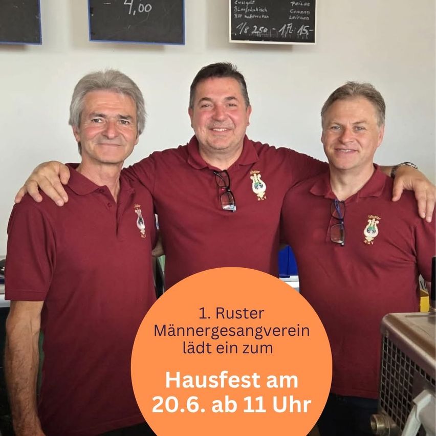 Drei Männer in kastanienbraunen Poloshirts posieren für ein Foto. Sie stehen eng beieinander. Hinter ihnen befindet sich eine weiße Wand mit zwei Tafeln und einem Schild, das 'Hausfest am 20.6. ab 11 Uhr' besagt.