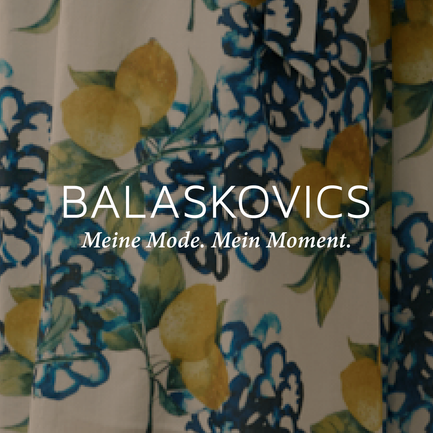 Ein Bild eines Vorhangs mit blauem Blumendesign und Zitronen in der Mitte. Der Text lautet 'Balaskovics Meine Mode, Mein Moment.' Es handelt sich wahrscheinlich um eine Werbung für eine Modemarke.
