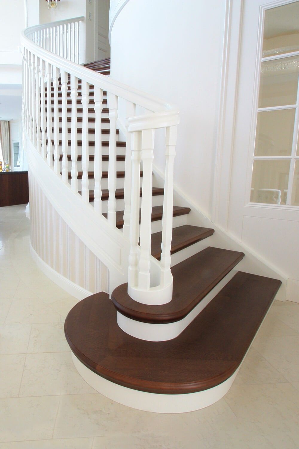 Eine elegante Wendeltreppe mit weißen Geländern und dunklen Holzstufen führt in einem modernen Interieur in die obere Etage.