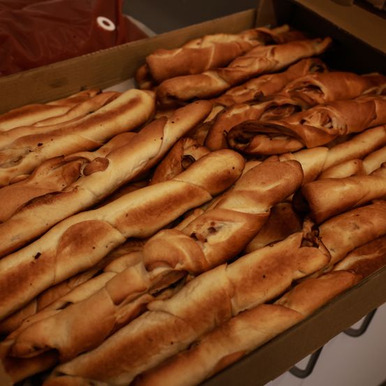 Ein Pappkarton voller Reihen gerollter, goldbrauner und leicht angebrannter Brötchen, bereit zum Servieren.