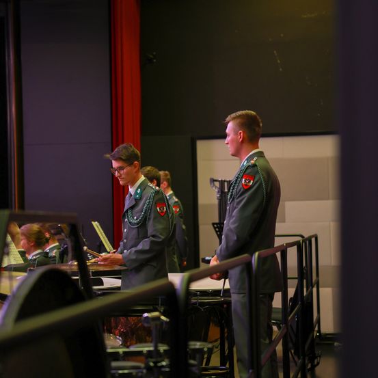 Eine Militärkapelle bereitet sich auf eine Aufführung auf der Bühne vor, mit einem Schlagzeuger und einem Trompeter in Uniform.