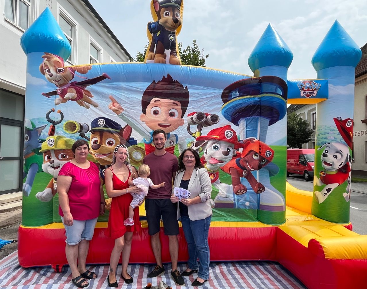 Fünf Personen stehen vor einem großen aufblasbaren PAW-Patrol-Zeichen. Sie lächeln für die Kamera.
