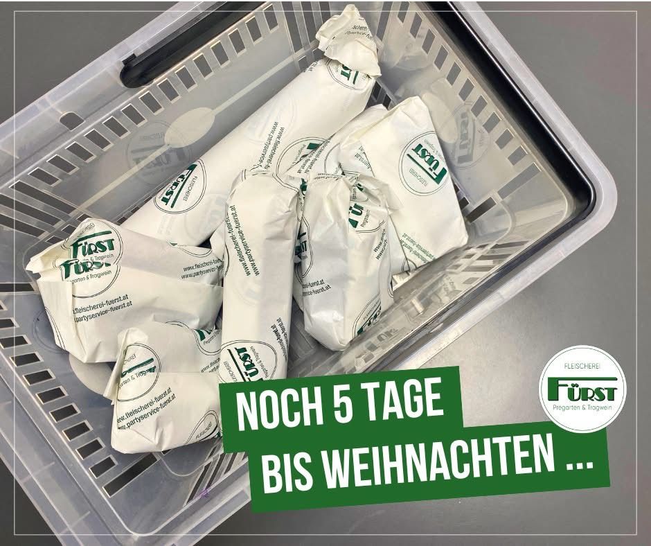Ein Plastikbehälter enthält mehrere verpackte Fleischprodukte mit dem Etikett 'Fleischerei Furst'. Das Etikett zeigt '5 Tage bis Weihnachten'. Der Behälter steht auf einer Metalloberfläche.