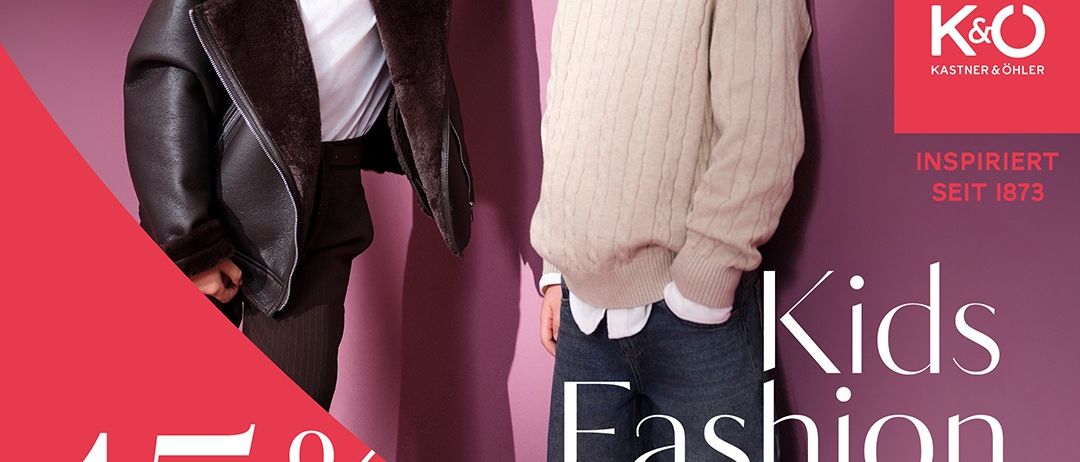 Ein Junge und ein Mädchen stehen nah beieinander vor einem rosa Hintergrund. Der Junge trägt einen beigen Pullover und Jeans, und das Mädchen trägt eine schwarze Jacke und ein weißes T-Shirt. Der Text lautet '15% Rabatt auf Kindermode' und 'Kids Fashion Week 1-14.9.2025'.