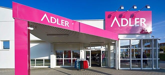 Der Vordereingang eines Geschäfts mit dem Namen Adler. Der Eingang ist pink und hat große Buchstaben. Es hängen Kleidungsstücke an den Gestellen.