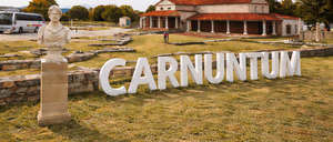Two images merged: a fire truck labeled 'Flughafen Wien Feuerwehr' and a historical site at Carnuntum with a statue.