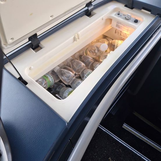 Ein offener Kühlschrank mit mehreren Wasserflaschen darin. Der Kühlschrank ist weiß mit blauer Einfassung.