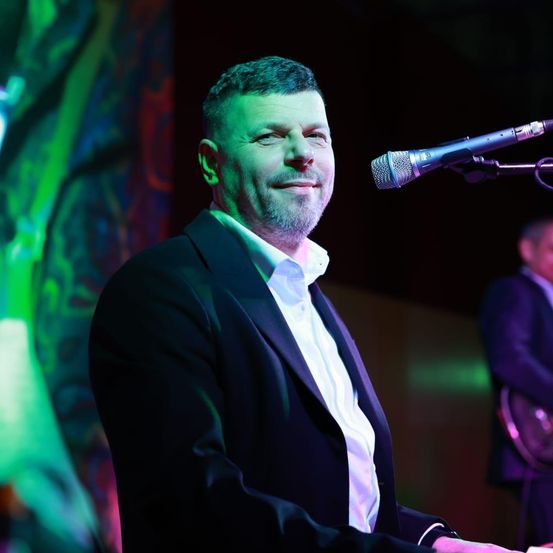 Bild enthält, Adult, Male, Man, Person, Microphone, Performer, Solo Performance, Guitar, Suit, Face