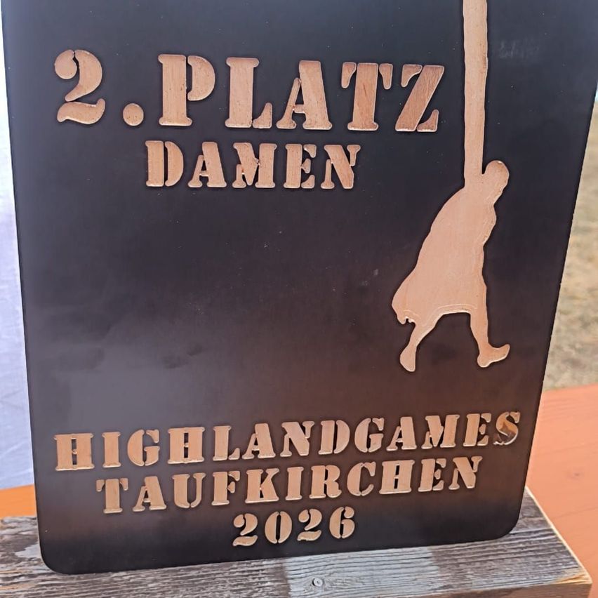 A black plaque with gold text reading '2. Platz Damen' and a silhouette of a person swinging from a rope. Below it, the words 'Highlandgames Taufkirchen 2026' are engraved.