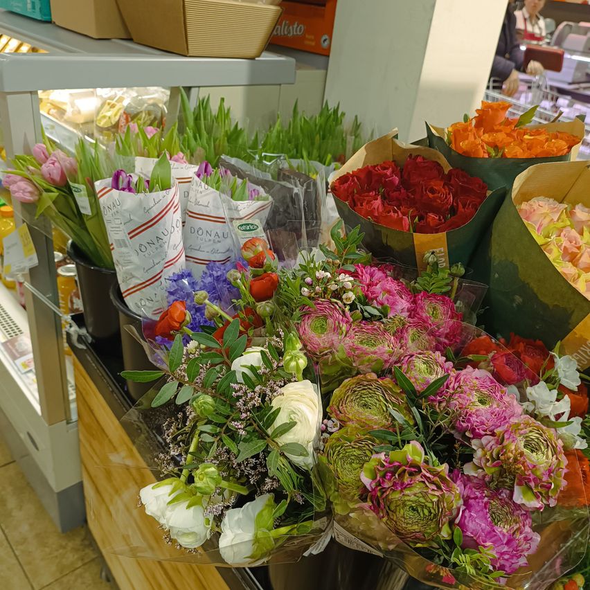 Ein Blumenladen mit einer Vielzahl von Blumenarrangements, darunter Rosen, Tulpen und andere farbenfrohe Blumen, auf einem Tresen ausgestellt.