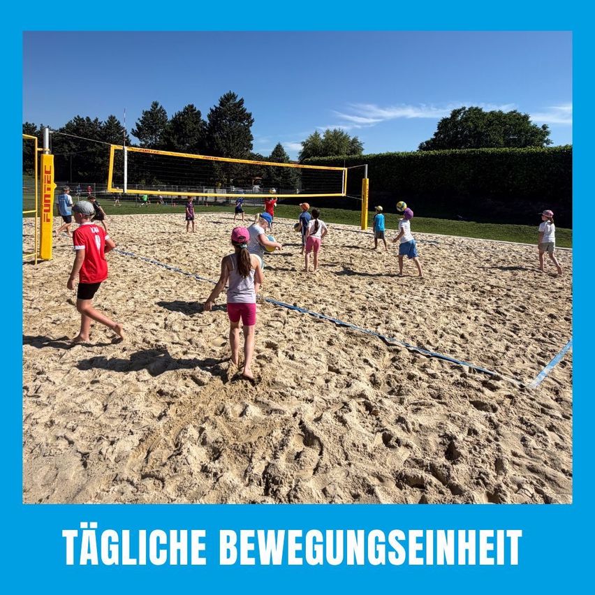 Eine Gruppe von Kindern spielt Volleyball auf einem Sandplatz, einige tragen Helme. Ein gelbes Netz trennt die beiden Teams.