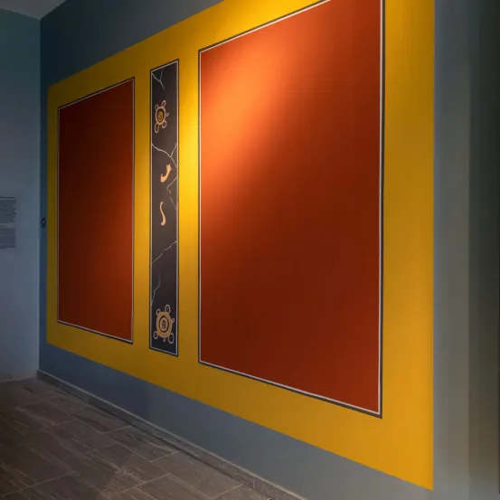 Eine Wand mit drei Tafeln, zwei große orangefarbene an den Seiten und eine kleinere in der Mitte, mit einem schwarzen und orangefarbenen Design.