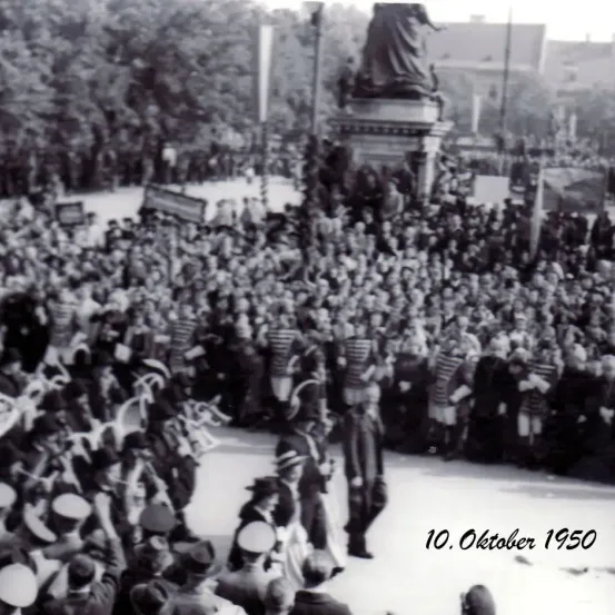Ein Schwarz-Weiß-Foto zeigt eine große Menschenmenge um ein Denkmal, datiert auf den 10. Oktober 1950. Viele Personen tragen Hüte, und einige sind in Uniformen.