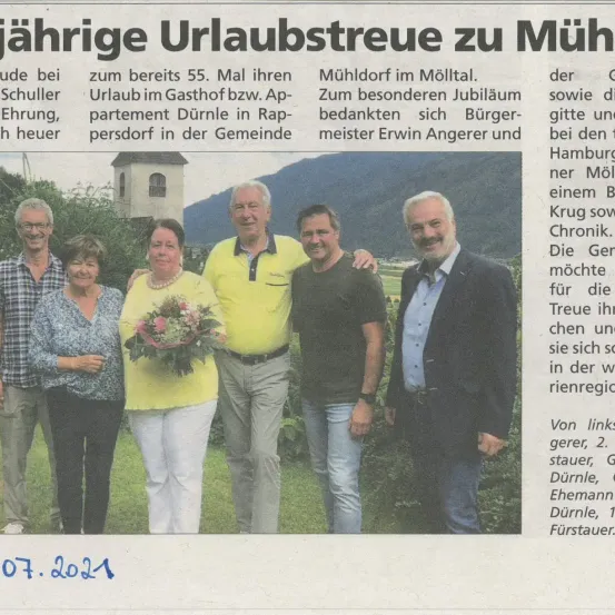 Ein Zeitungsausschnitt zeigt sechs lächelnde Personen. Eine Frau hält einen Blumenstrauß. Die Überschrift lautet 'Jährliche Urlaubsreise zu Mühl bei Schuller' mit dem Datum Juli 2021.