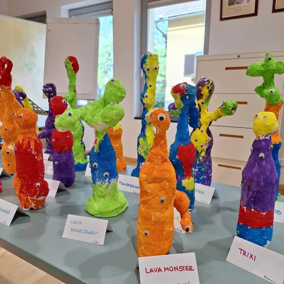 Ein Tisch mit einer Sammlung bunter Skulpturen namens Lava Monster, ausgestellt auf einem weißen Hintergrund mit Etiketten.