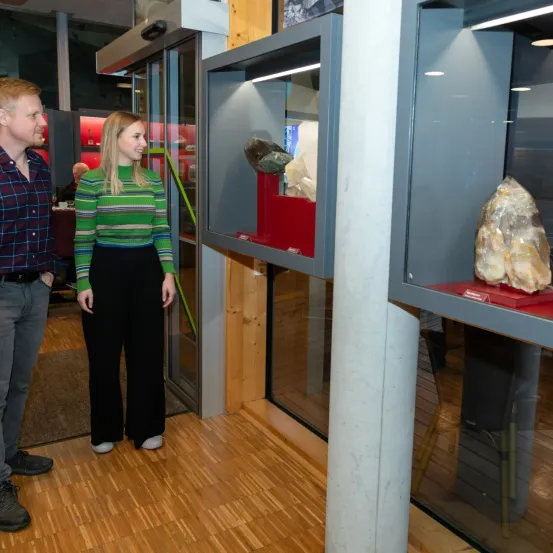 Ein Mann und eine Frau stehen in einem Gebäude und betrachten eine Glasvitrine mit großen Steinen.