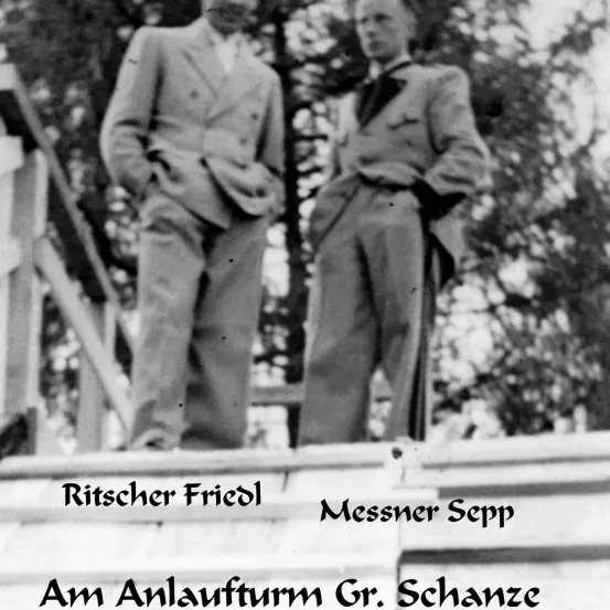 Zwei Männer in formeller Kleidung stehen auf einer Holzplattform, möglicherweise auf dem Gr. Schanze. Das Foto hat einen Schwarz-Weiß-Filter.