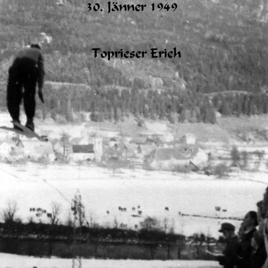 Ein Schwarz-Weiß-Foto zeigt einen Skifahrer, der am 30. Januar 1949 einen Sprung auf einer verschneiten Piste macht. Der Skifahrer heißt Toprieser Erich.