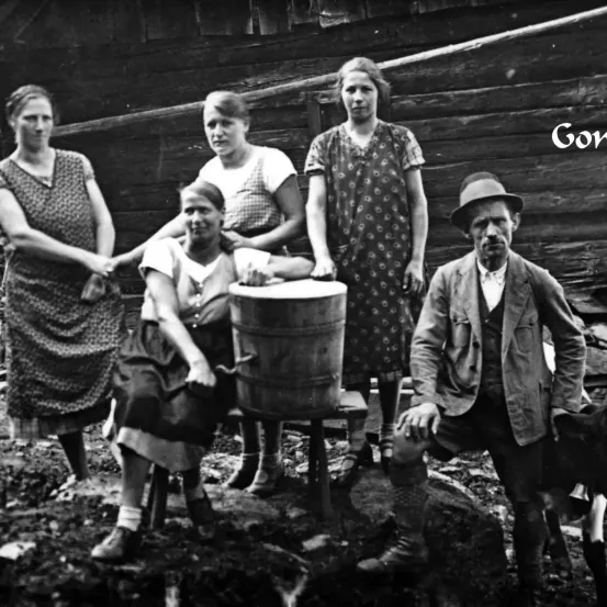 Ein Schwarz-Weiß-Foto einer Familie, die um einen Holzfass steht. Fünf Personen lächeln und posieren für die Kamera.