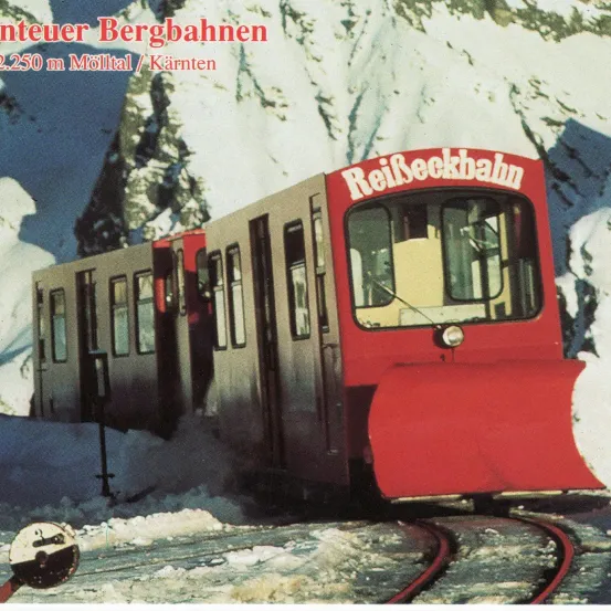 Ein roter Zug mit dem Wort 'ReilSeckbahn' darauf, umgeben von verschneiten Bergen.
