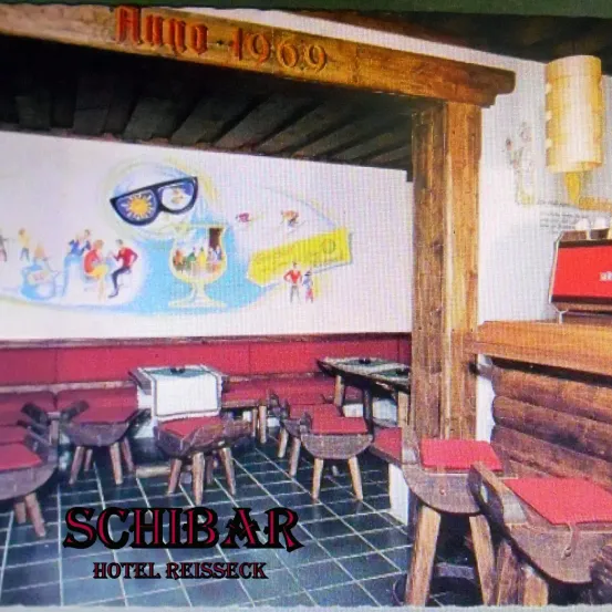 Innenansicht der Schibar im Hotel Reisseck in Österreich, mit einer Wandmalerei von Menschen, die die Sonne genießen, Tischen und Holzstühlen. Der Tresen ist im Vordergrund zu sehen.
